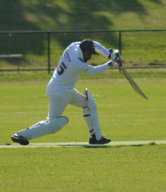 A man batting in the field, with wearing of whites
